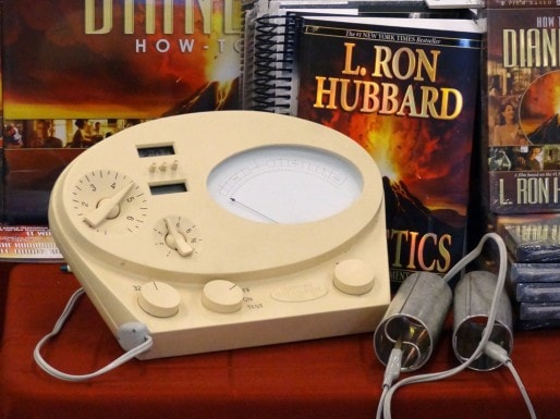 Un électromètre avec, en arrière plan, le livre de Ron Hubbard (Wikipedia)