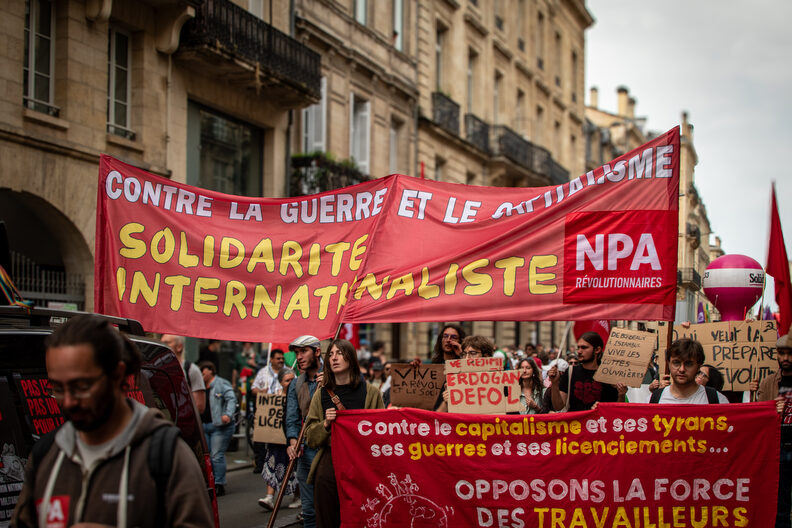 Militants du NPA à Bordeaux lors du défilé du 1er mai 2025, brandissant une banderole appelant à la solidarité ouvrière face à l’économie de guerre.