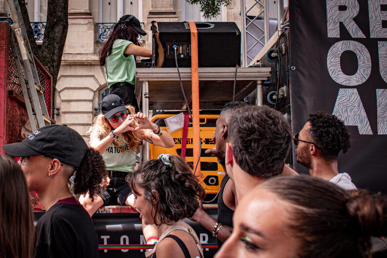 Participants et participantes de la Pride 2025 à Bordeaux défilent dans les rues, arborant drapeaux arc-en-ciel, pancartes militantes LGBTQIA+ et tenues colorées.