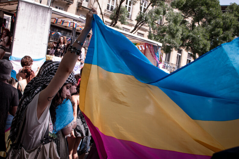 Participants et participantes de la Pride 2025 à Bordeaux défilent dans les rues, arborant drapeaux arc-en-ciel, pancartes militantes LGBTQIA+ et tenues colorées.