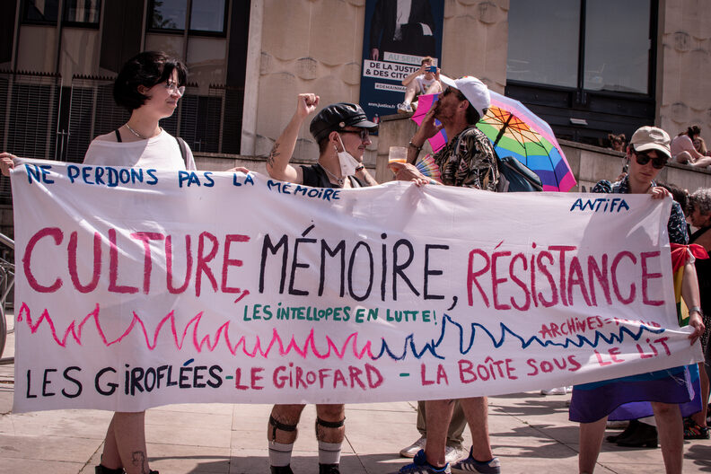 Participants et participantes de la Pride 2025 à Bordeaux défilent dans les rues, arborant drapeaux arc-en-ciel, pancartes militantes LGBTQIA+ et tenues colorées.