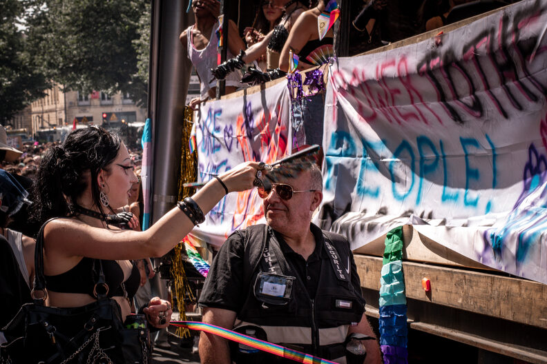 Participants et participantes de la Pride 2025 à Bordeaux défilent dans les rues, arborant drapeaux arc-en-ciel, pancartes militantes LGBTQIA+ et tenues colorées.